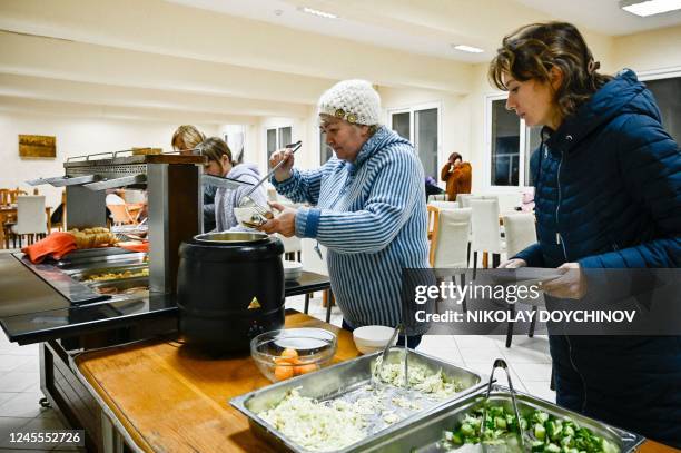 Ukrainian refugees serve food to themselves in a dining room of a children's holiday camp, run by a Russian investor and where they found refuge, on...