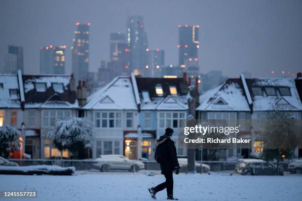Commuter walks past residential properties after low temperatures and overnight snowfall on south London homes on Ruskin Park in SE24, on 12th...