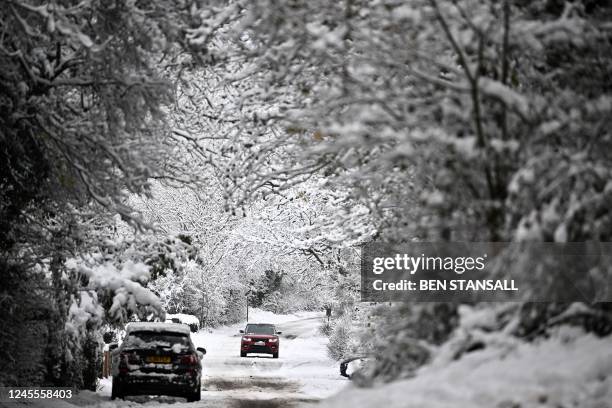 Car is driven along a snow-covered lane in Brenchley, south east England, on December 12, 2022.