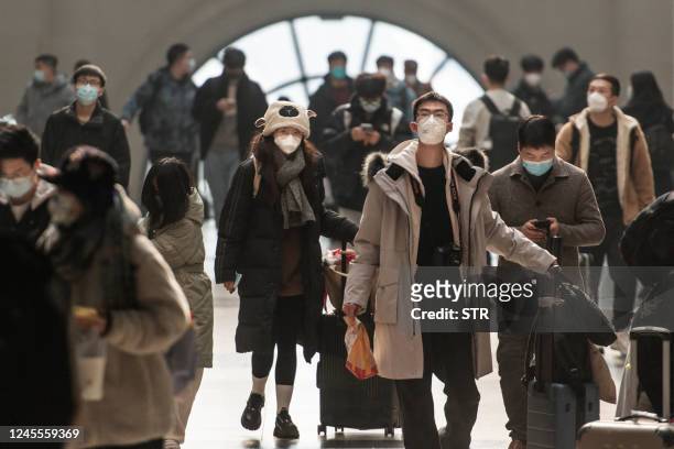 This photo taken on December 10, 2022 shows passengers wearing face masks amid the Covid-19 pandemic arriving at Hankou Railway Station in Wuhan in...