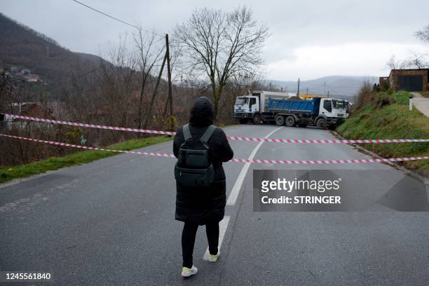 Woman walks towards a road barricade set up with trucks by ethnic Serbs in the village of Rudare near the town of Zvecan on December 12, 2022. -...