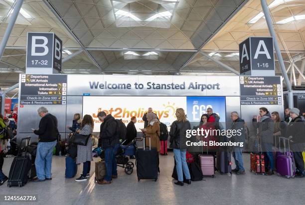 Passengers queue at the check-in area at London Stansted Airport, operated by Manchester Airport Plc, in Stansted, UK, on Monday, Dec. 12, 2022. With...
