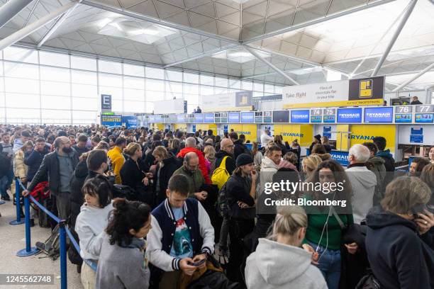 Passengers queue for Ryanair Holdings Plc flights at the check-in area at London Stansted Airport, operated by Manchester Airport Plc, in Stansted,...