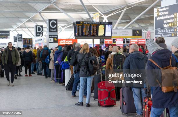 Passengers queue at the check-in area at London Stansted Airport, operated by Manchester Airport Plc, in Stansted, UK, on Monday, Dec. 12, 2022. With...