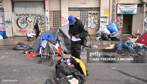 Homeless people stand with their belongings in front of an outpatient mental health clinic in Los Angeles, California, on December 6, 2022. - A state...