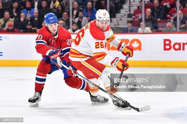 Michael Stone of the Calgary Flames skates the puck against Juraj Slafkovsky of the Montreal Canadiens during the second period at Centre Bell on...