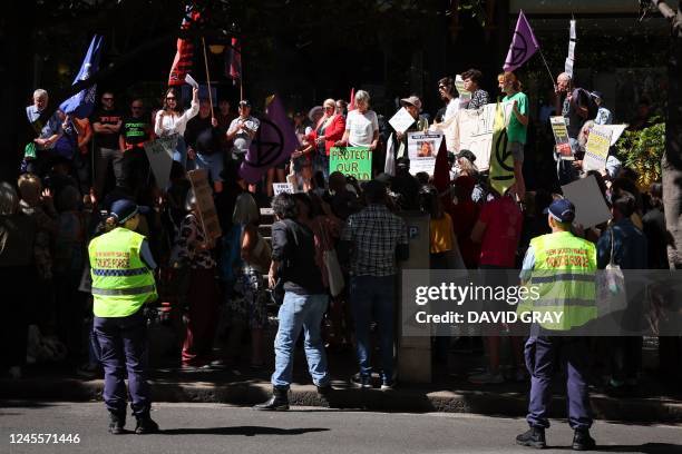 Police officers stand in front of protesters holding placards and banners during a rally in support of climate activist Deanna "Violet" Coco, who...