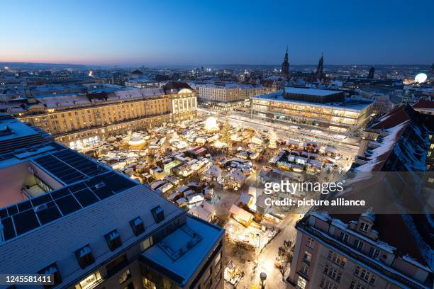 December 2022, Saxony, Dresden: Brightly lit are the snow-covered stalls at the Striezelmarkt. The Christmas market at Dresden's Altmarkt is open...