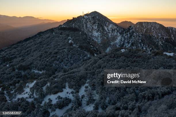 In an aerial view, cloudless weather at sunrise in the snow-covered San Gabriel Mountains is seen as a massive storm leaves California to spread...