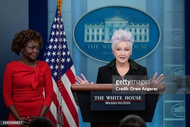 White House Press Secretary Karine Jean-Pierre looks on as Singer Cyndi Lauper speaks during the daily press briefing at the White House December 13,...