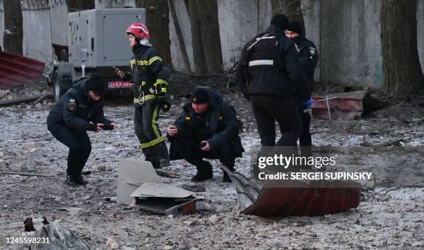 Rescuers and police experts examine remains of a drone following a strike on an administrative building in the Ukrainian capital Kyiv on December 14,...