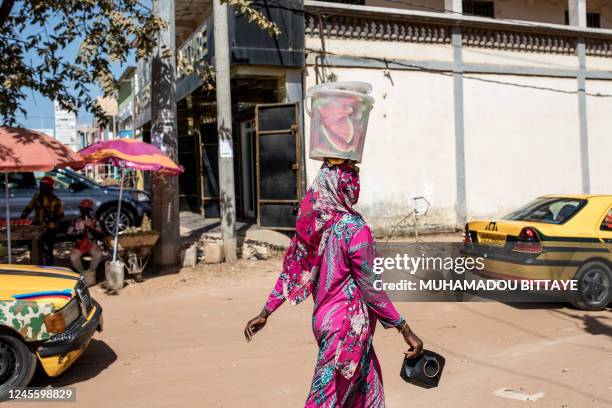 Woman walks with a bucket of watermelon slices on her head in Banjul on December 8, 2022. Watermelon season is very popular in Gambia, the refreshing...