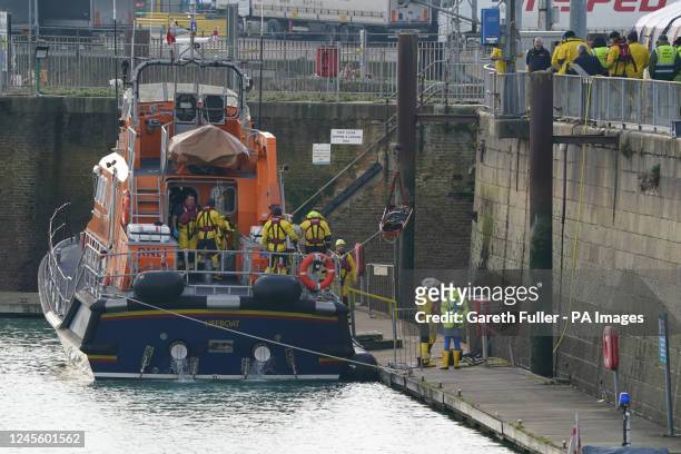 Emergency staff remove a stretcher and body bag from the Dover lifeboat after it returned to the Port of Dover following a large search and rescue...