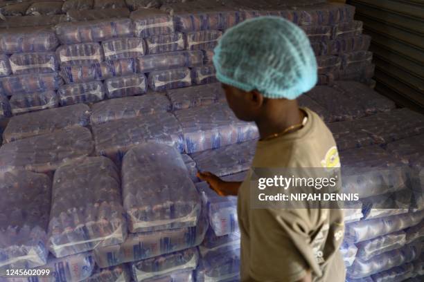 Factory worker packs sachets of treated drinking water in plastic bags at a factory in Accra, Ghana, on December 1, 2022. - Ghana is battling its...