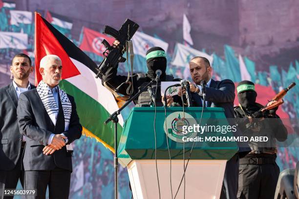 Yahia al-Sinwar , Gaza Strip chief of the Palestinian Islamist Hamas movement, stands by as a masked fighter of Hamas' Qassam Brigades holds up a...