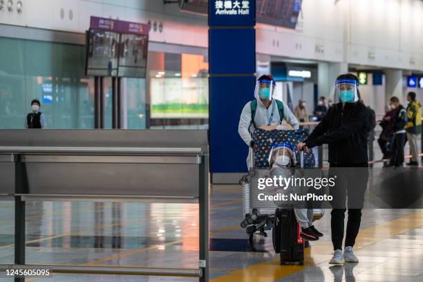 Girl, a woman and a man with luggages wearing a face shield at the arrival hall inside Terminal 1 at Hong Kong International Airport on December 14,...