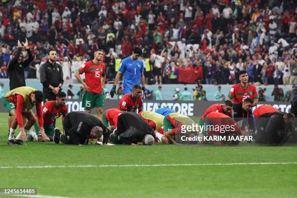 Morocco's players kneel in prayer at the end of the Qatar 2022 World Cup semi-final football match between France and Morocco at the Al-Bayt Stadium...