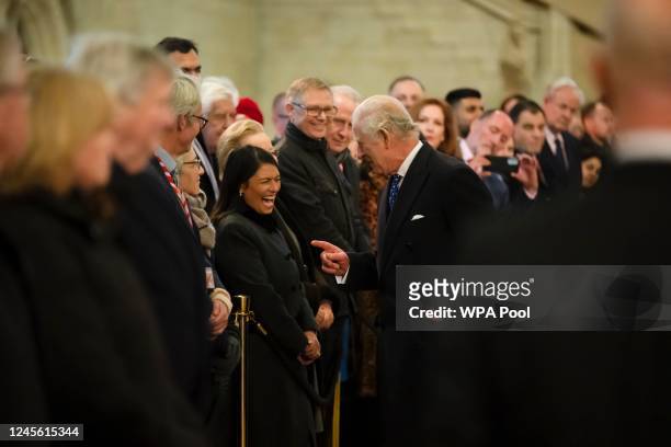 King Charles III laughs with Priti Patel MP as he visits the Houses of Parliament to see a new plaque commemorating HM Queen Elizabeth II laying in...