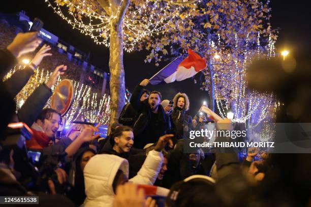 Football fan holds the French flag as he celebrates after France's victory over Morocco in the Qatar 2022 World Cup semi-final, on the Champs-Elysees...