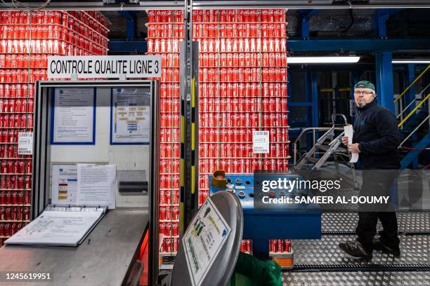 In this photograph taken on December 12, 2022 a worker controls packed soft drink cans manufactured at Ball Packaging in Bierne, northern France....