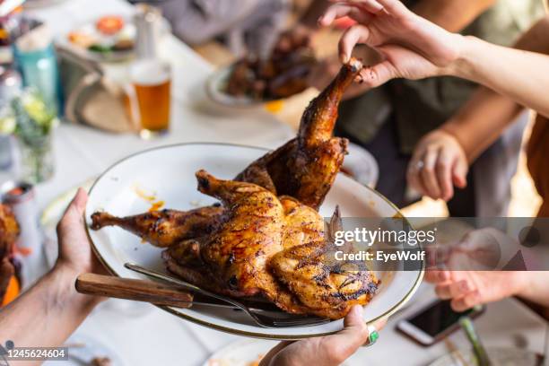 people grabbing chicken off the a serving plate at a family style wedding dinner. - chicken meat fotografías e imágenes de stock