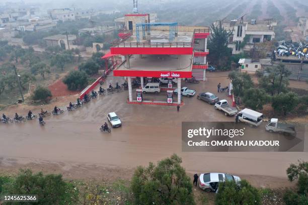 Syrians queue up to fills their tanks outside a gas station in an area controlled by jihadists of the Hayat Tahrir al-Sham group, which controls much...