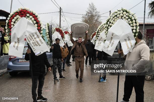 Members of the Roma community in Greece hold funeral wreaths during the funeral of a 16-year-old Roma boy who was shot in the head by Greek police,...