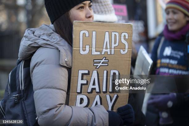 Demonstrators, holding placards and banners, gather to protest wage increase offered under inflation and working conditions during a strike by NHS...