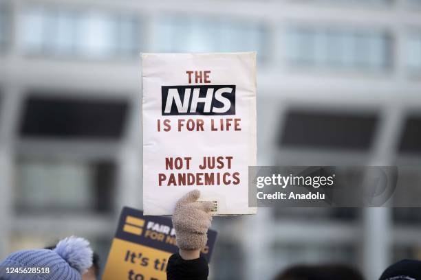 Demonstrators, holding placards and banners, gather to protest wage increase offered under inflation and working conditions during a strike by NHS...