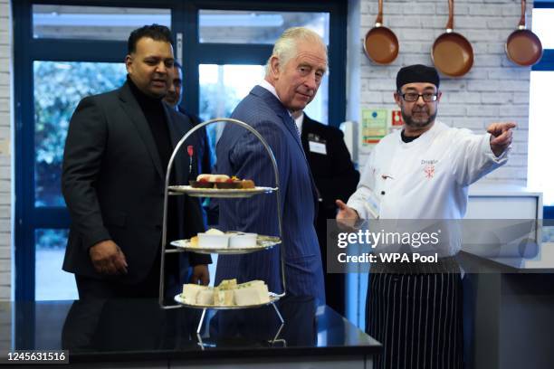 Britain's King Charles III reacts as he meets with volunteers and members of staff during a visit of the London's Community Kitchen facilities on...