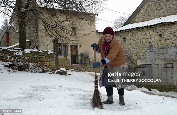 Une personne âgée balaie la neige devant son domicile, le 28 janvier 2005 à Chaptuzat , alors que la circulation est délicates, voire très difficile...
