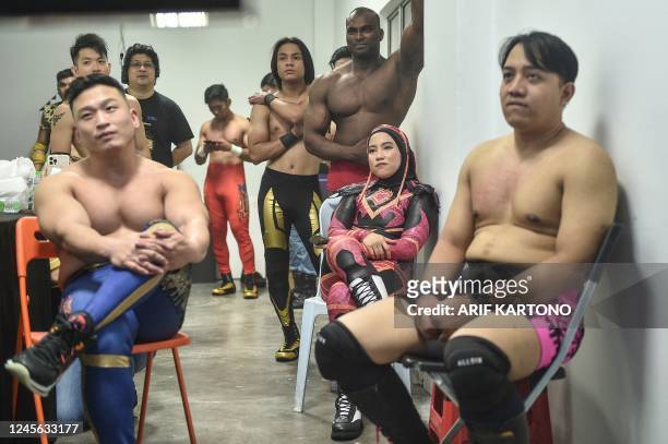 This picture taken on December 10, 2022 shows Malaysian hijab-wearing wrestler Nor Phoenix Diana and male wrestlers watch in the backstage a live...