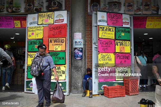 Woman holds a grocery bag in front of a store displaying signs with dollar prices at the Quinta Crespo municipal market in Caracas on December 15,...