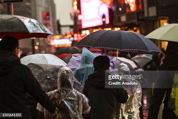 People walk through the rain and sleet in Manhattan as temperatures begin to fall on December 15, 2022 in New York City. A winter storm moving into...
