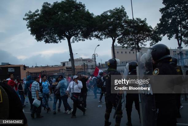 Demonstrators run from tear gas as riot police officers attempt to control the crowd during protests on Avenida de Pierola in Lima, Peru, on...