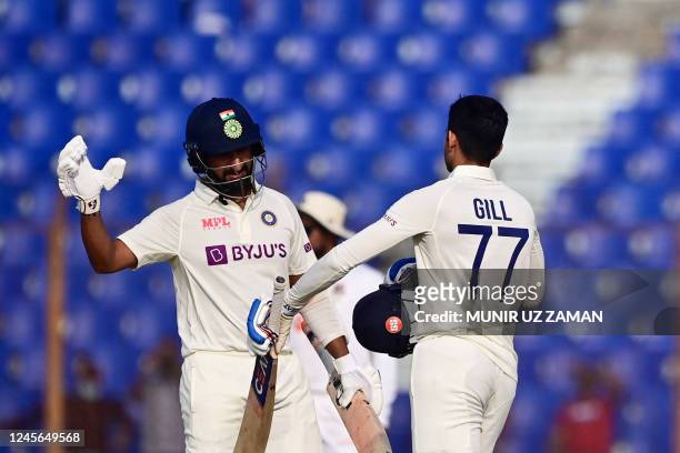 Indias Shubman Gill shakes hands with his teammate Cheteshwar Pujara after scoring a century during the third day of the first cricket Test match...