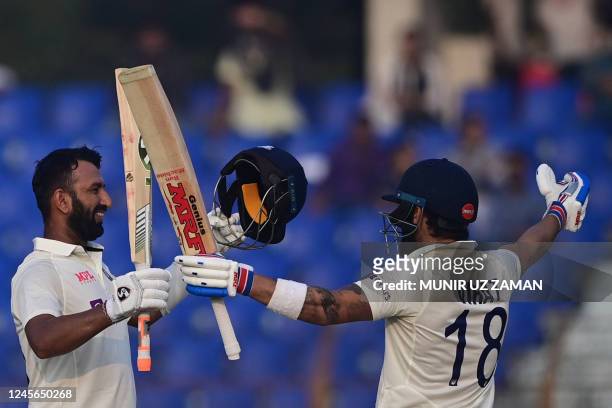 Indias Cheteshwar Pujara celebrates after scoring a century with Virat Kohli during the third day of the first cricket Test match between Bangladesh...