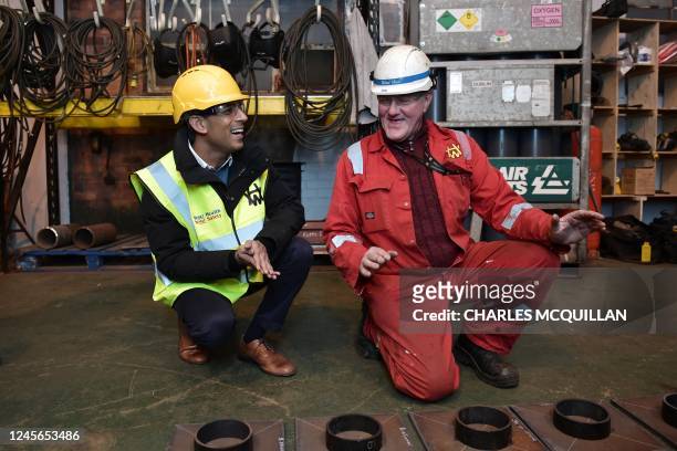 Britain's Prime Minister Rishi Sunak speaks with welder Brian Walsh as he visits the Harland & Wolff shipyard factory, on December 16, 2022 in...
