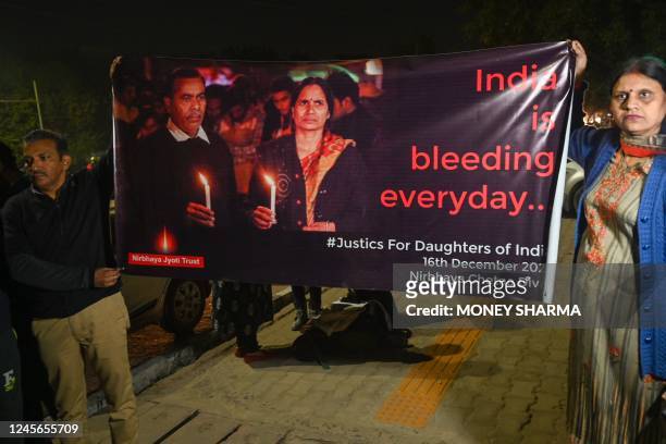 People hold a poster during a candlelight vigil on the tenth anniversary of the heinous gang rape of a young woman, in New Delhi on December 16,...