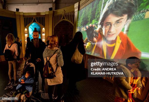 Visitors walk past a screen showing an excerpt of a film during the opening of the European exhibition of Harry Potter in Vienna, Austria on December...