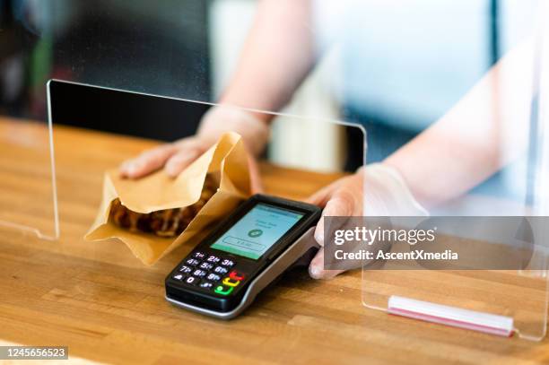 contactless payment terminal with a sneeze guard for covid-19 - sneeze guard stock pictures, royalty-free photos & images