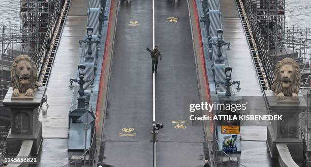 Cameraman walks on the partially renovated Chain Bridge in Budapest on December 16, 2022. - Two lanes of the oldest permanent bridge across the...