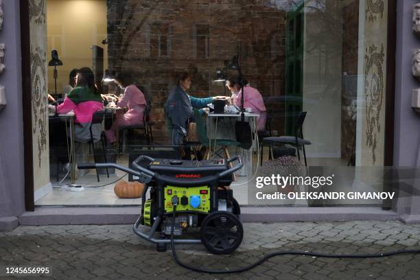 People sit in a nail salon which electricity comes from a power generator outside standing outside in the center of Ukrainian city of Odessa during...