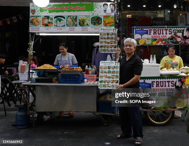Thai street food vendor displays the food menu at his cart in Bangkok's world famous Khao San Road backpacker tourist accommodation, shopping and...