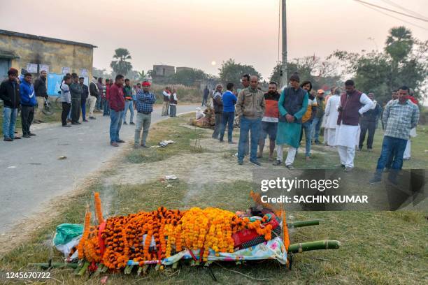 Villagers gather near a body of a victim before the last rites, who lost his life after consuming locally made tipple known as "Mahua" or "Desi Daru...