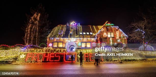 Strollers walk past a house illuminated with Christmas outdoor decoration in Buecken, northern Germany on December 16, 2022.