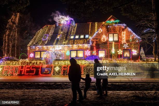 Strollers walk past a house illuminated with Christmas outdoor decoration in Buecken, northern Germany on December 16, 2022.