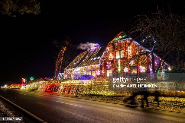 Strollers walk past a house illuminated with Christmas outdoor decoration in Buecken, northern Germany on December 16, 2022.