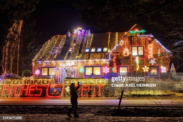 Woman takes a photo of a house illuminated with Christmas outdoor decoration in Buecken, northern Germany on December 16, 2022.