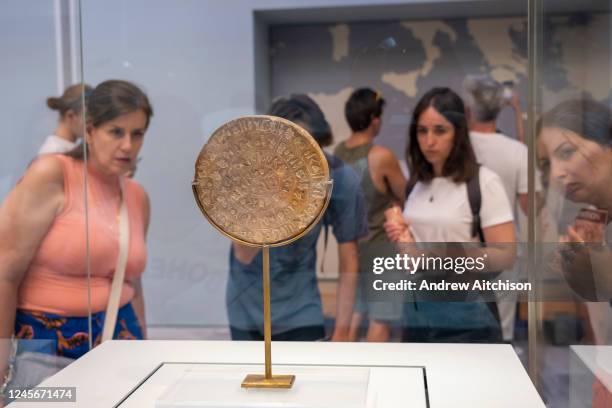 Tourists looking at the Phaistos Disc inside the archaeological museum of Heraklion in Crete that hold the most important and complete collection of...